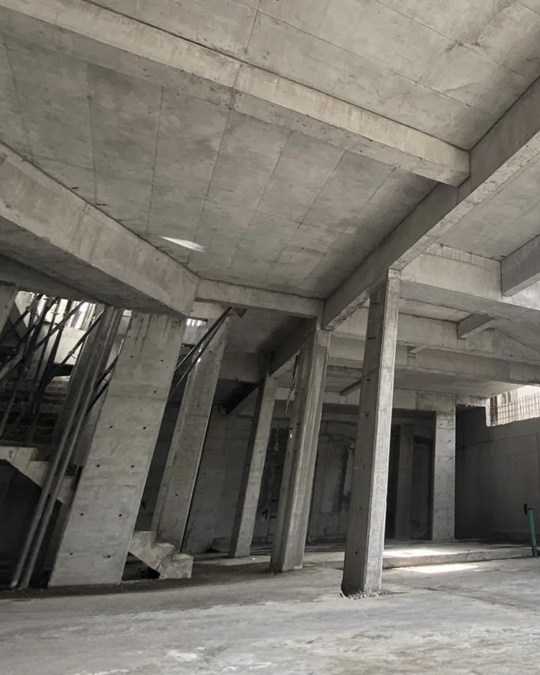 Interior view of a reinforced concrete building frame showing columns, beams, slab ceiling, and staircase structure after formwork removal.